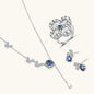 Sterling silver jewelry set with rainbow moissanite stones in clover and butterfly designs on cream background
