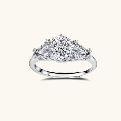 Sterling silver ring with oval moissanite center stone surrounded by smaller accent stones in ornate setting