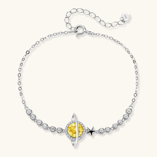 Sterling silver bracelet with yellow moissanite centerpiece in oval setting, crystal chain, and star charm on white background.