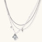 Multi-strand layered necklace set with silver chains, white pearls, star charm, heart pendant, and ornate decorative piece
