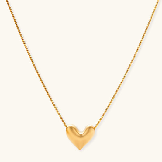 Dainty 18K gold-plated sterling silver necklace with small heart pendant on delicate chain against cream background.