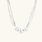 Sterling silver multi-strand necklace with three brushed round beads on cream background