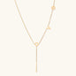 Gold Y-shaped necklace with L-O-V-E letter charms and vertical bar pendant on delicate chain against cream background