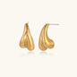 Organic sculptural gold stud earrings with fluid matte finish on cream background