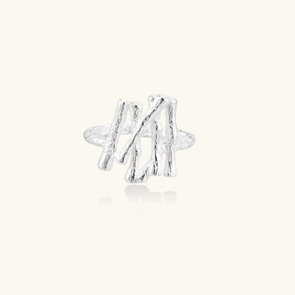 Sculptural sterling silver ring with organic branch design and textured surfaces on cream background