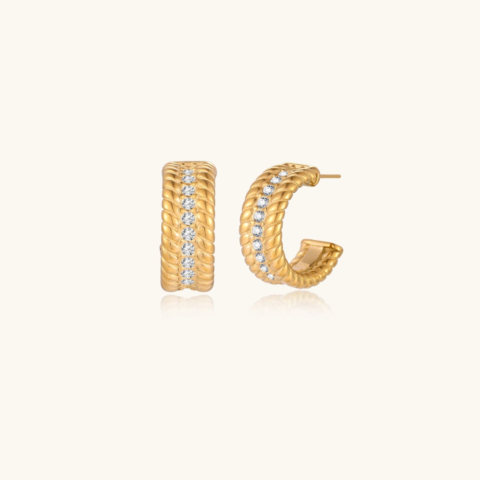 Textured gold huggie hoop earrings with raised ribbed rows creating dimensional sculptural design on cream background