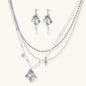 Ornate silver-toned masquerade mask jewelry set featuring rhinestone details and pearl drop earrings on white background.