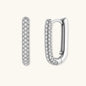 Close-up of platinum-plated sterling silver huggie hoops with pavé crystal setting on white background.